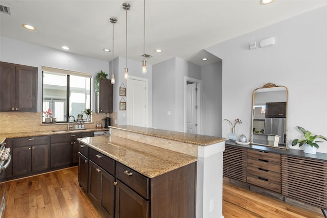 kitchen featuring a center island, visible vents, a sink, and dark brown cabinets