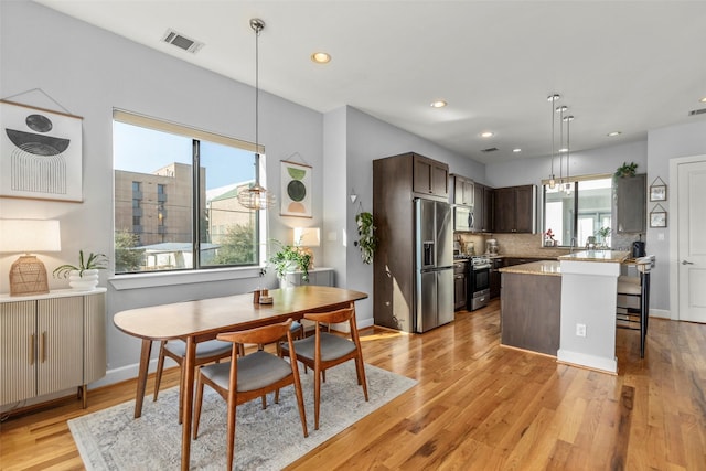 kitchen featuring stainless steel appliances, visible vents, dark brown cabinets, light countertops, and light wood finished floors