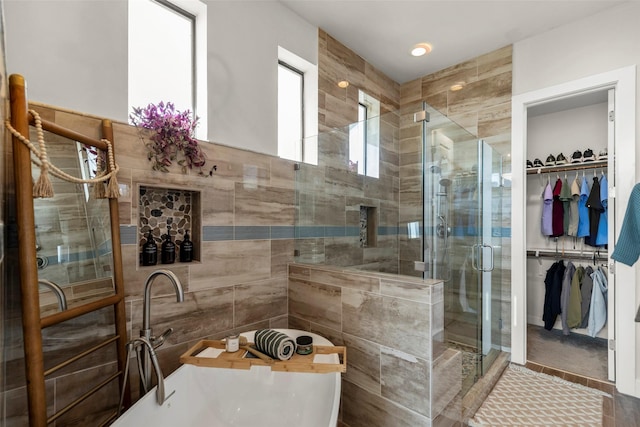 full bath featuring a spacious closet, a freestanding tub, and a shower stall