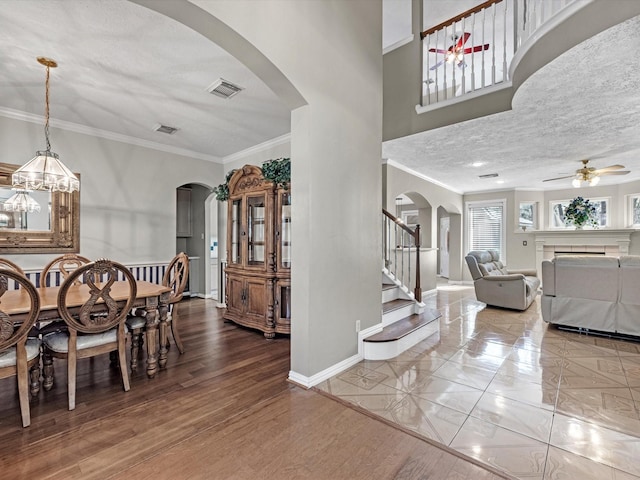 dining space with a textured ceiling, arched walkways, visible vents, baseboards, and stairway