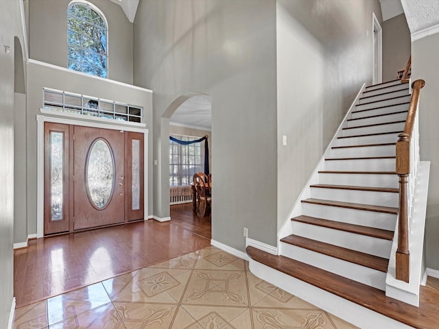 tiled entrance foyer with arched walkways, plenty of natural light, a towering ceiling, and baseboards