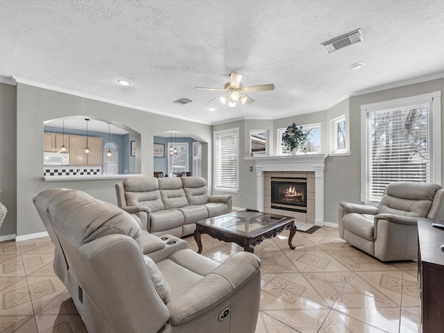 living room featuring visible vents, a wealth of natural light, and a tile fireplace