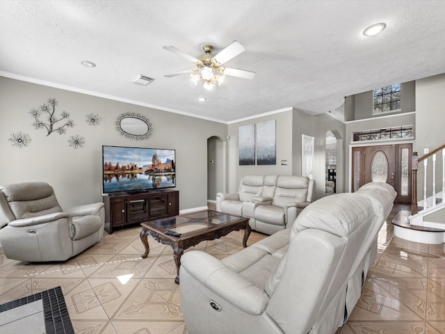 living room with arched walkways, visible vents, stairway, and a textured ceiling