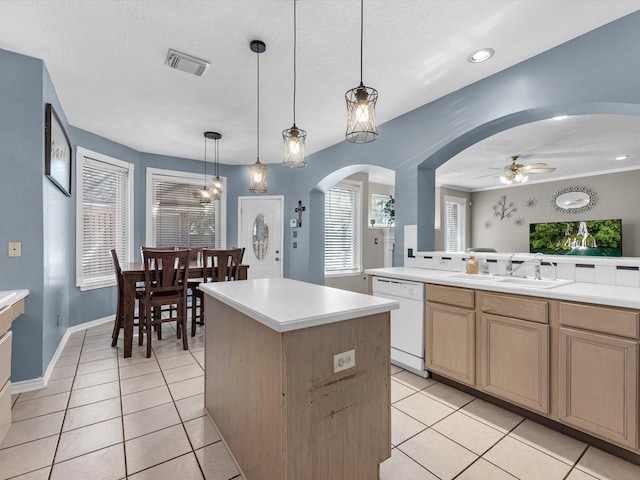 kitchen featuring light tile patterned floors, white dishwasher, a sink, and a center island