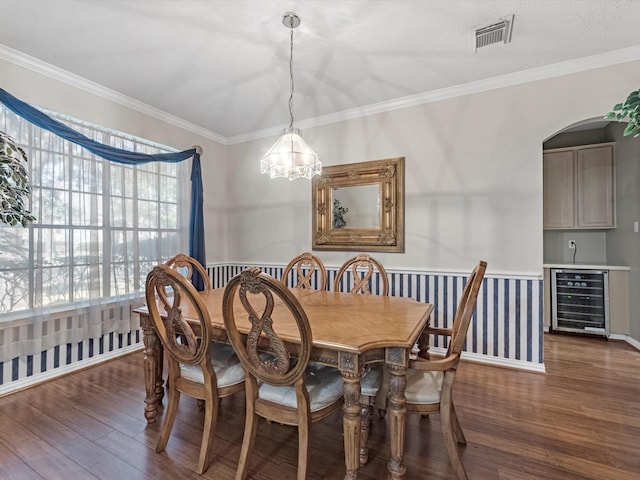 dining space featuring ornamental molding, beverage cooler, visible vents, and wood finished floors