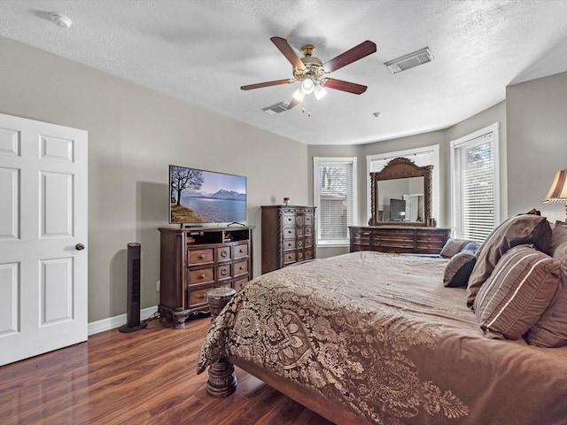 bedroom featuring a textured ceiling, wood finished floors, visible vents, and baseboards