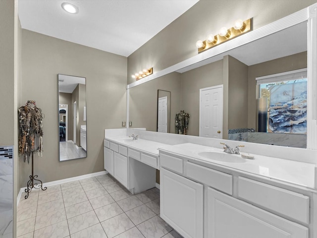 full bath with double vanity, tile patterned flooring, a sink, and baseboards