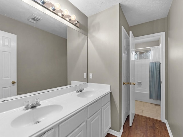 bathroom featuring double vanity, visible vents, a sink, and wood finished floors