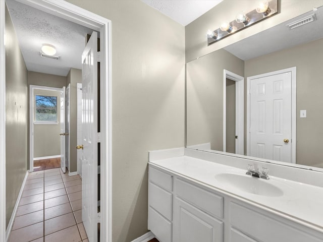 bathroom featuring a textured ceiling, tile patterned flooring, vanity, visible vents, and baseboards