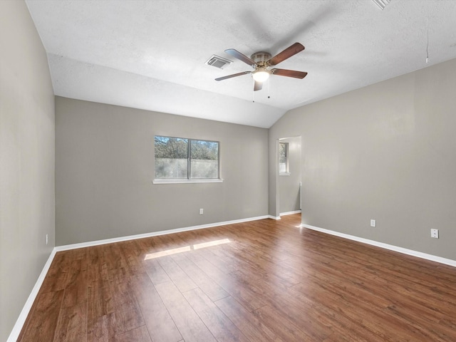 spare room featuring a ceiling fan, visible vents, baseboards, and wood finished floors