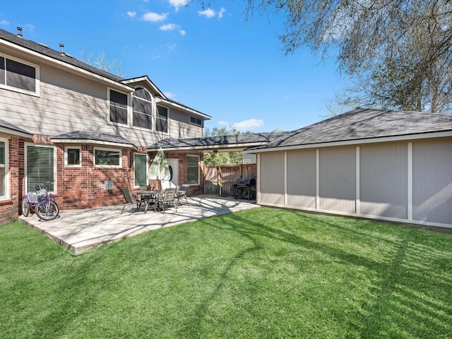 rear view of property with a yard, brick siding, a patio, and fence