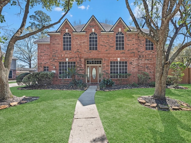 view of front of house with brick siding, a front lawn, and fence