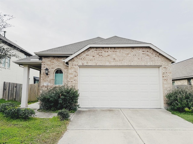 view of front facade featuring brick siding, driveway, an attached garage, and fence