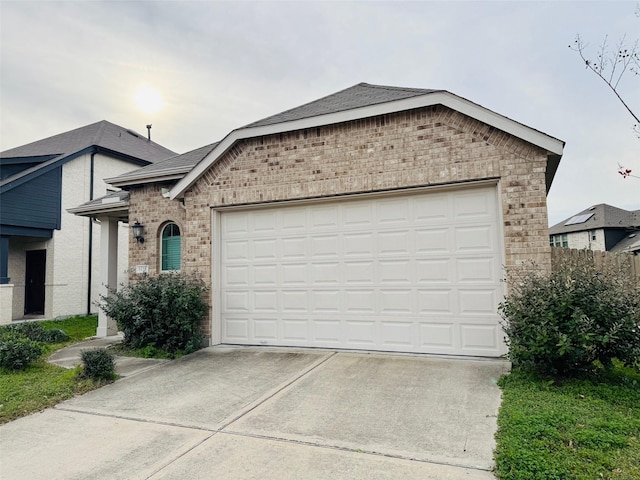 view of front of property with a garage, concrete driveway, brick siding, and roof with shingles