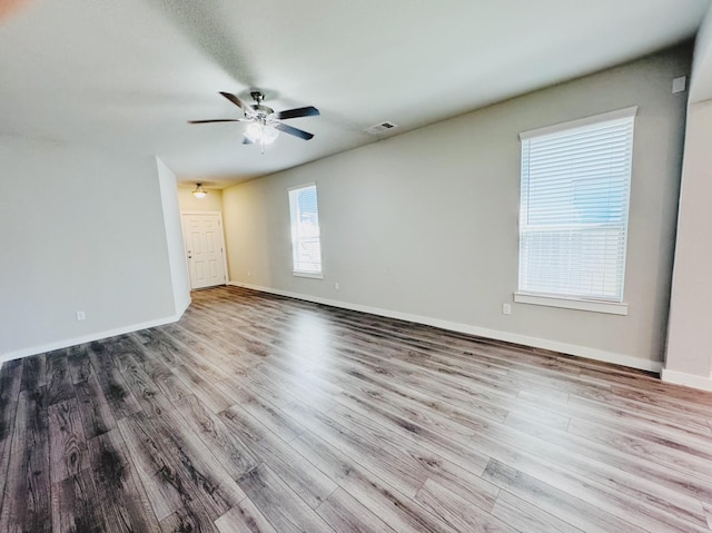 unfurnished room featuring a ceiling fan, wood finished floors, visible vents, and baseboards