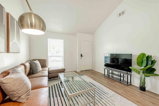 living area featuring visible vents, vaulted ceiling, and wood finished floors