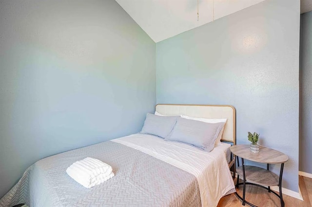 bedroom with lofted ceiling, baseboards, and wood finished floors