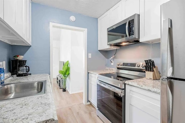 kitchen featuring light wood-style floors, white cabinetry, appliances with stainless steel finishes, and a sink