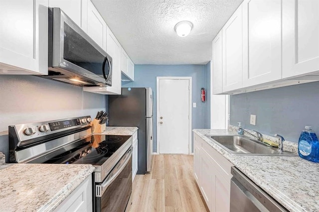 kitchen with stainless steel appliances, a sink, and white cabinets