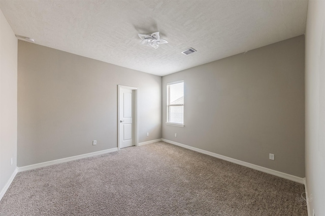 spare room featuring visible vents, baseboards, a textured ceiling, and light colored carpet