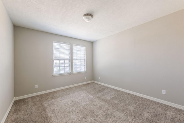 spare room with carpet, baseboards, and a textured ceiling