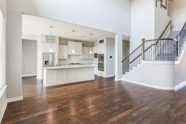 kitchen featuring baseboards, white cabinets, appliances with stainless steel finishes, dark wood-style flooring, and pendant lighting