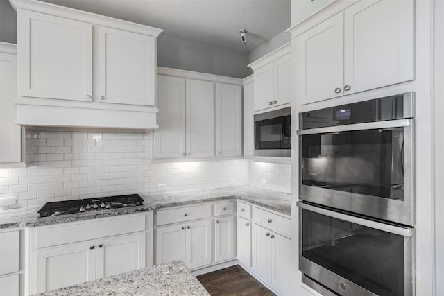 kitchen featuring appliances with stainless steel finishes, white cabinets, premium range hood, and tasteful backsplash