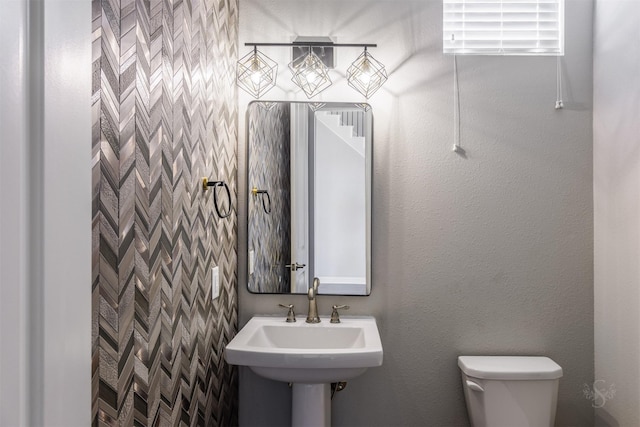 bathroom featuring a textured wall, a sink, and toilet