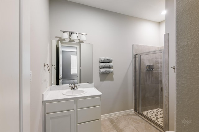 bathroom with baseboards, a shower stall, and vanity