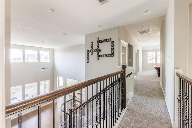 corridor with visible vents, light carpet, and an upstairs landing