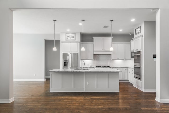 kitchen with tasteful backsplash, appliances with stainless steel finishes, dark wood-style flooring, a kitchen island with sink, and a sink