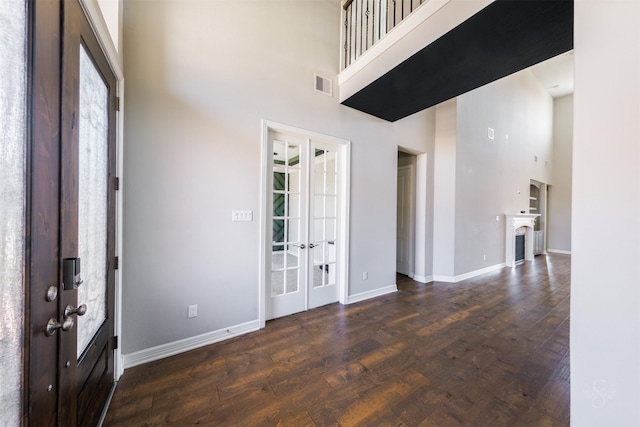 entrance foyer featuring french doors, dark wood-type flooring, a towering ceiling, and visible vents