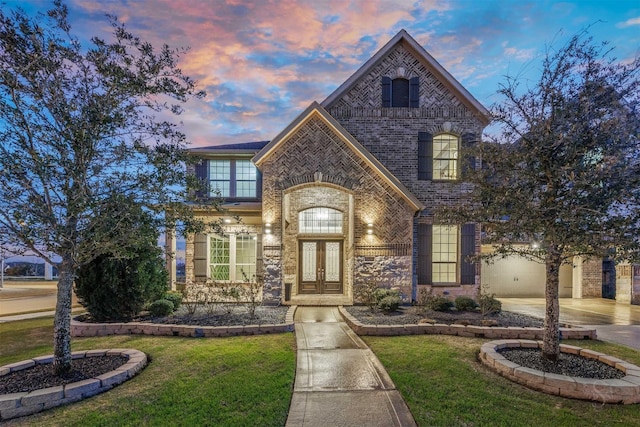 french provincial home featuring a garage, concrete driveway, french doors, a front yard, and brick siding