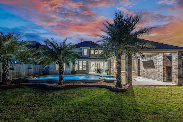 view of pool with a yard, a patio, fence, and a pool with connected hot tub