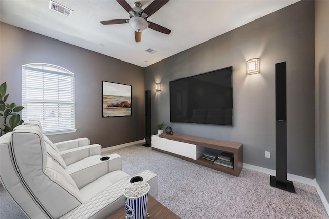 carpeted home theater with a ceiling fan, visible vents, and baseboards