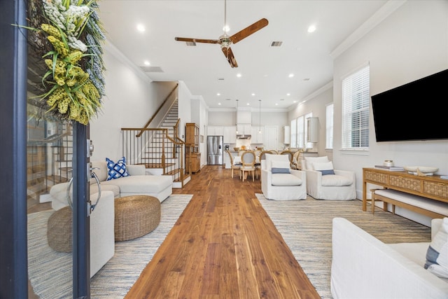 living area featuring recessed lighting, visible vents, stairway, light wood-type flooring, and crown molding