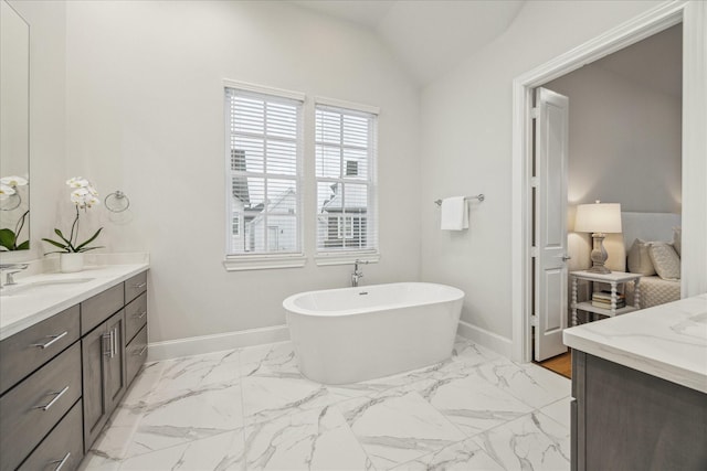 full bath featuring vaulted ceiling, a freestanding tub, vanity, and baseboards