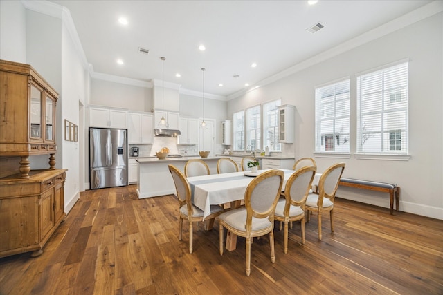 dining area with dark wood-type flooring, visible vents, crown molding, and baseboards