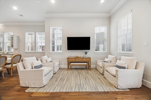 living area featuring crown molding, wood finished floors, visible vents, and baseboards