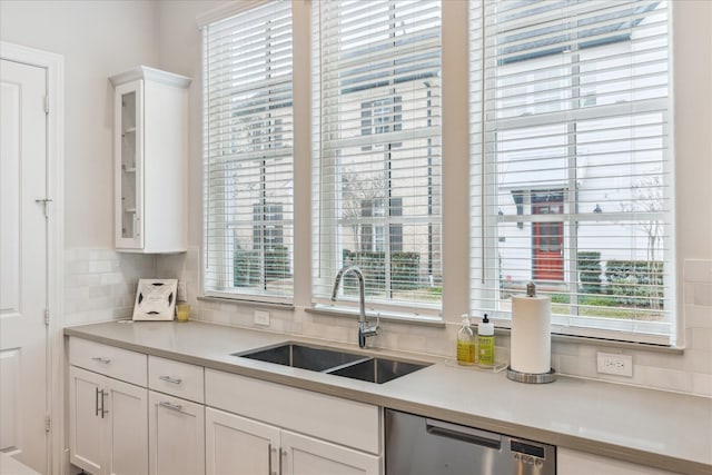 kitchen featuring a sink, plenty of natural light, white cabinetry, and dishwasher