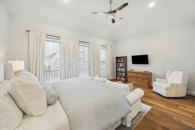 bedroom with multiple windows, visible vents, vaulted ceiling, and wood finished floors