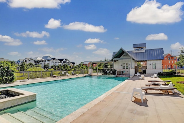 pool with a patio area, fence, and a residential view