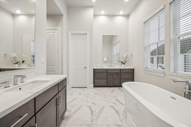 full bath featuring marble finish floor, a soaking tub, a sink, and recessed lighting