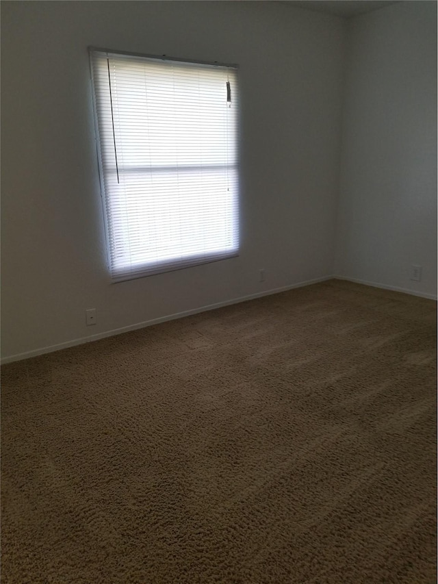 spare room featuring carpet flooring and baseboards