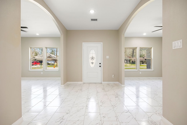 foyer featuring marble finish floor, a wealth of natural light, and a ceiling fan