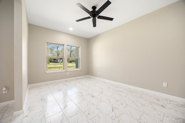 unfurnished room with marble finish floor, a ceiling fan, and baseboards