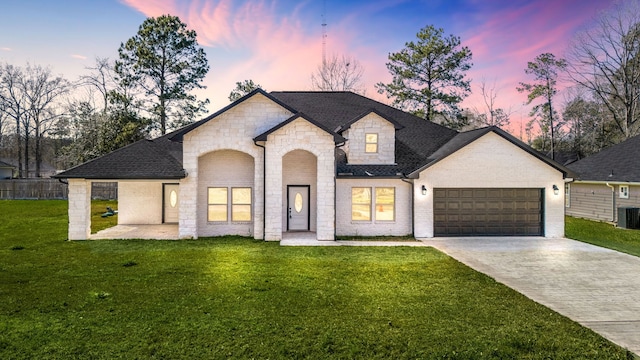 french country style house featuring a garage, a lawn, concrete driveway, and brick siding