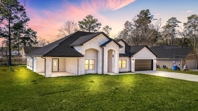 french country home with driveway, a lawn, an attached garage, and fence