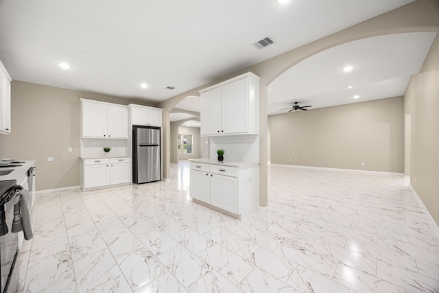 kitchen with visible vents, arched walkways, decorative backsplash, and freestanding refrigerator