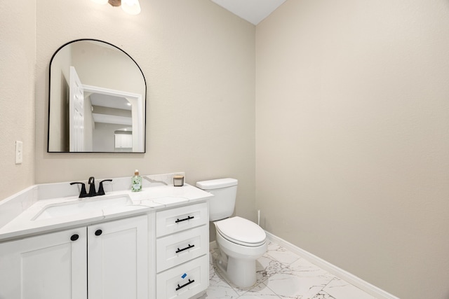 bathroom with toilet, marble finish floor, vanity, and baseboards